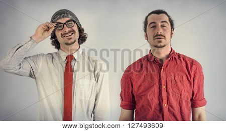 Twin adult men with beards exchange a pair of glasses