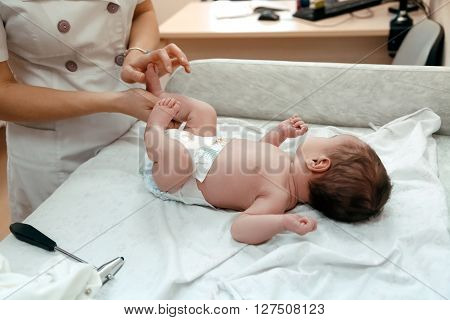 Pediatrician examining littlle newborn baby on the table