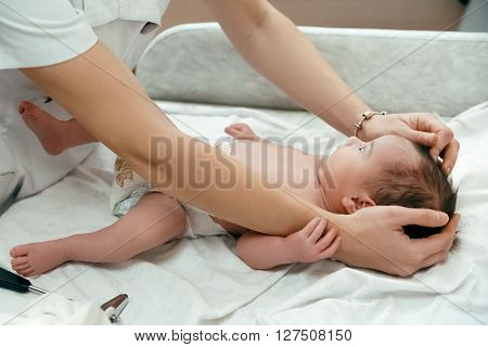 Pediatrician examining littlle newborn baby on the table