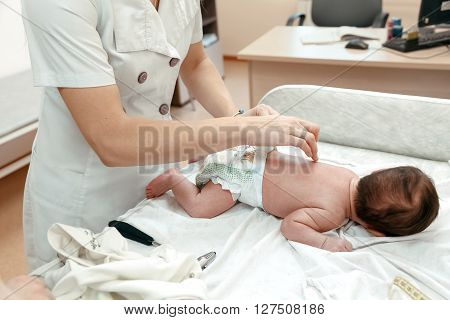 Pediatrician examining littlle newborn baby on the table