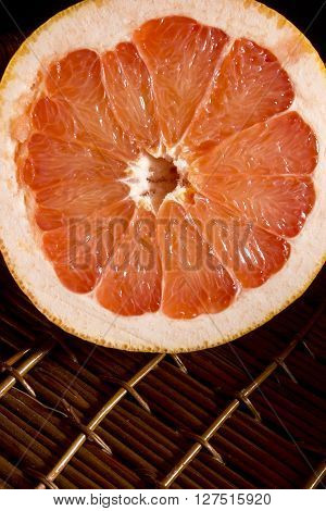 Cut half of juicy ripe grapefruit on wicker surface