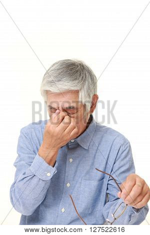 studio shot of senior Japanese man suffers from Asthenopia on white background