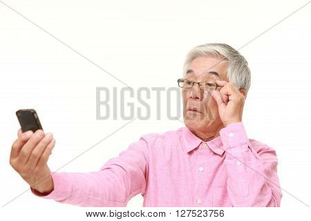 senior Japanese man with presbyopia on white background