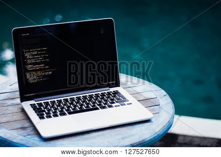 laptop on a wooden table against the background of accepted Swimming pool