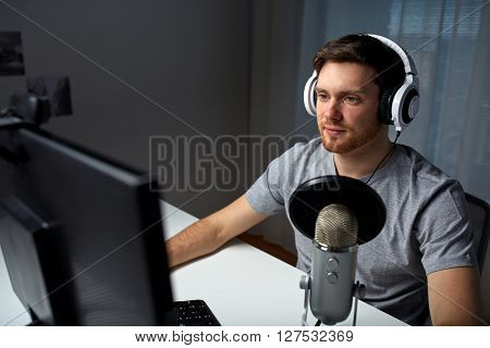 technology, gaming, entertainment, let's play and people concept - happy young man in headset with pc computer playing game at home and streaming playthrough or walkthrough video