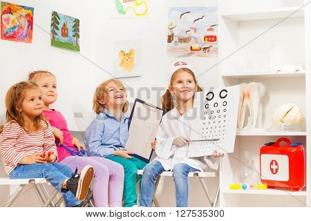 Happy little oculist and patients sitting at the doctor's room