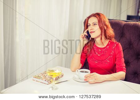 Beautiful  woman using 
laptop, phone at table in cafe