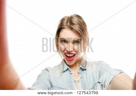 Closeup of beautiful playful woman making selfie photo on isolated white background and looking at camera