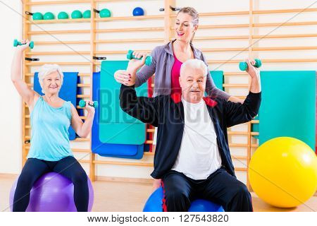 Physiotherapist coaching senior people exercising with dumbbells