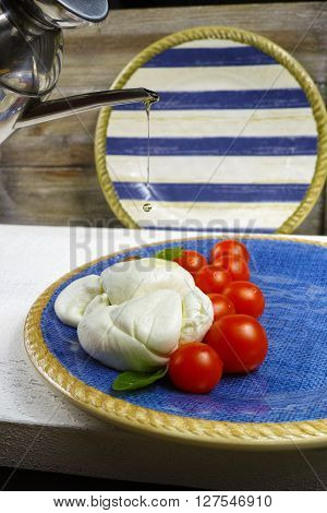 Traditional italian mozzarella buffala with tomatoes and basil on blue plate copy space