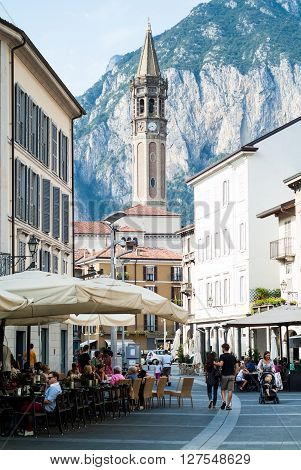 Lecco, Italy - September 1st 2015: People enjoying themselves in Piazza XX Settembre on September 1st 2015 in Lecco Italy with Basilica of Saint Nicholas (Campanile di San Nicol