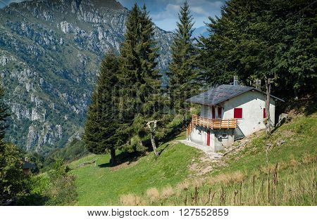photo of a sunlit traditional house at Piani d'Erna (part of the Alps) near Lake Como in Italy