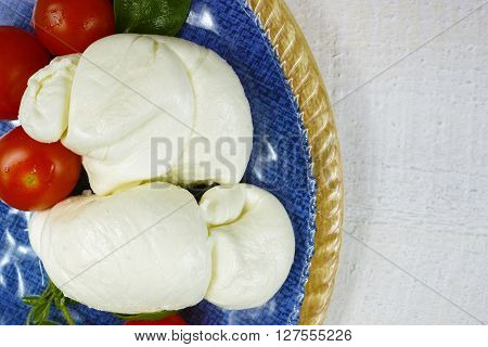 Traditional italian mozzarella buffala with tomatoes and basil on blue plate copy space