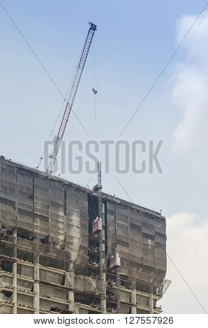 Building and crane under construction against blue sky