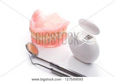 Teeth Model With Dental Floss And Mouth Mirror On White Background