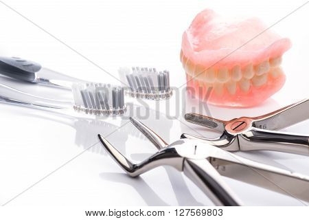 Teeth Model With Toothbrush And Forceps On White Background