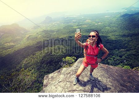 young woman hiker use smartphone taking self photo on seaside
