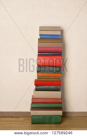 Old colorful books on wooden floor near the white wall