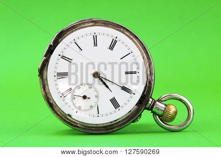 Old gold pocket watch isolated on green background