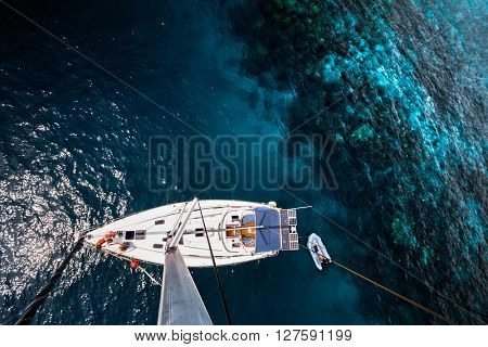 Aerial shot of the sailing boat anchored near the coral tropical reef