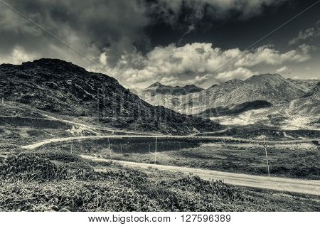 Beautiful curvy road passing through Jelepla Pass Dzuluk Sikkim India -with blue sky and clouds in the background. Black and white image