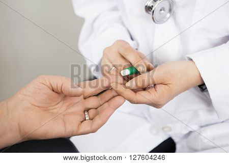 Doctor Using Tool On Patient's Finger For Blood Test