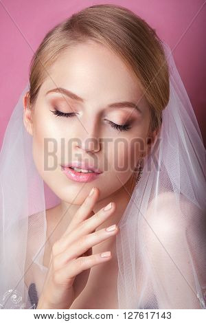 Young Gentle Quiet Bride in Classic White Veil. Portrait of beautiful bride. Beautiful Woman Touching her Face. Youth and Skin Care Concept. Beautiful woman with professional make up .