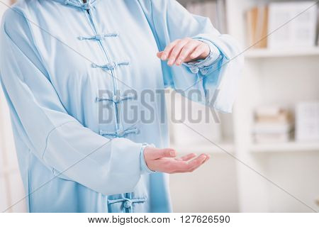 Beautiful woman doing qi gong tai chi exercise or reiki wearing professional, original Chinese clothes at home