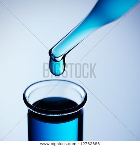 Provetta con pipetta su sfondo blu