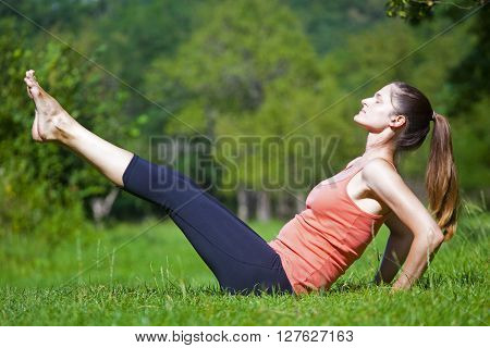 Young women practise yoga by day in nature