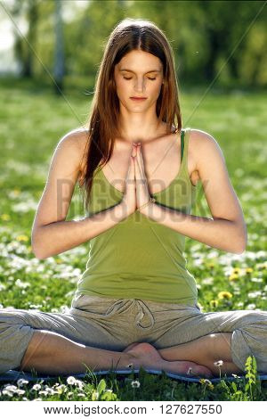 Young women practise yoga by day in nature