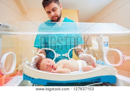 medical staff taking care of newborn baby in infant incubator