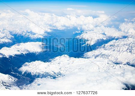 Snow covered mountains and rocky peaks in the French Alps, over blue sky. View from airplane