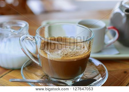 Morning cup of hot coffee with cream on table