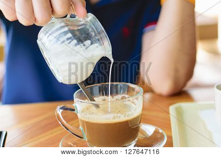 Morning cup of hot coffee with cream on table