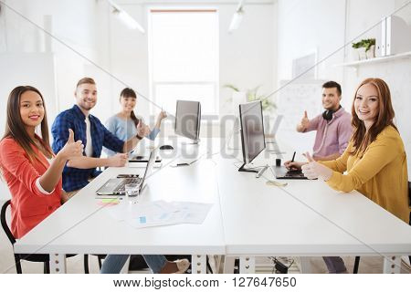 business, startup, success and people concept - creative team with computers, blueprint and scheme showing thumbs up at office