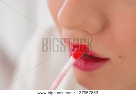 Sensual young woman applying cosmetics on her lips