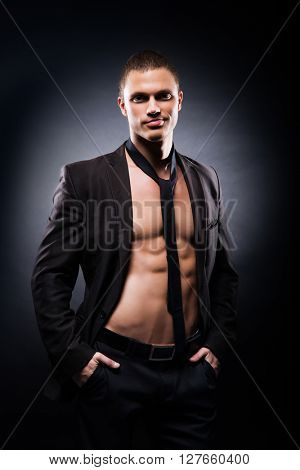 Strong, fit and sporty stripper man over black background