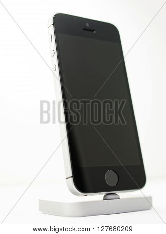 PARIS FRANCE - APR 21 2016: Front view of the new Apple iPhone SE in docking station combining the updated processor 4K rear camera touch id retina display