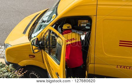 PARIS FRANCE - APR 21 2016: Courier enters DHL yellow delivery van after delivering the on time delivering package parcel