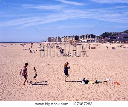 BARMOUTH, UK - AUGUST 6, 1995 - Holidaymakers on the beach with views towards the sea and town Barmouth Gwyedd Wales UK Western Europe, August 6, 1995.