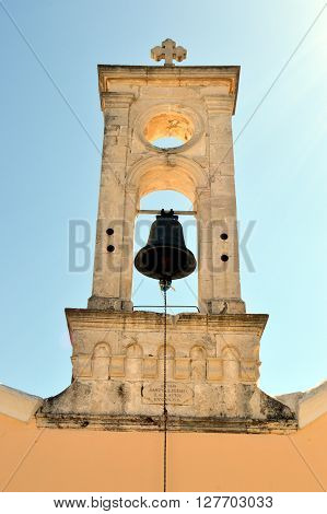 A white bell tower of color with a bell an eye of ox
