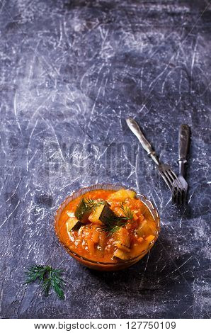 Homemade canned zucchini with vegetables in red sauce. Selective focus.