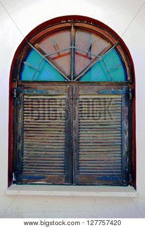 A wooden window with shutters and stained-glass windows.