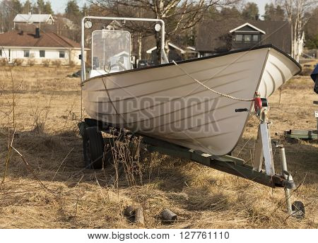 A small boat on a trailer on a yard for storing boats during non season