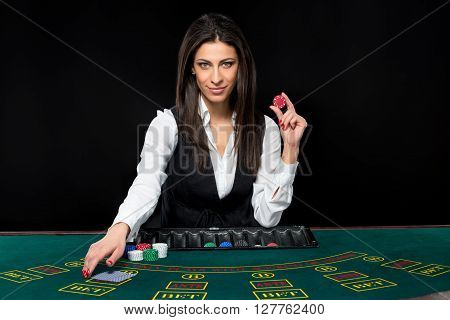 The beautiful girl, dealer, behind a table for game in poker. the dealer deals the cards.