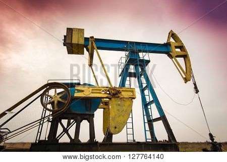 Sunset sky with profiled oil and gas well pump