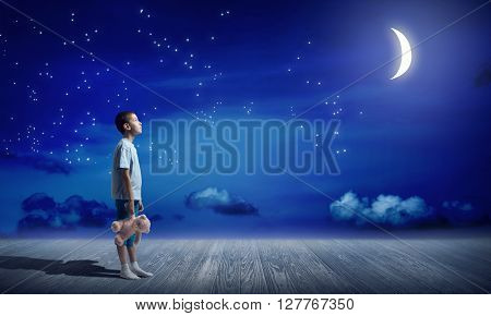 Cute kid boy wearing pajamas with bear toy in hand