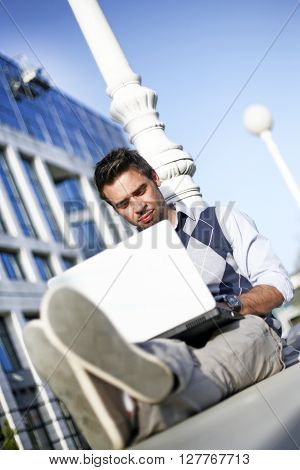 Young student working outside on his laptop