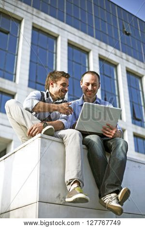 Two young students working together outside with laptop